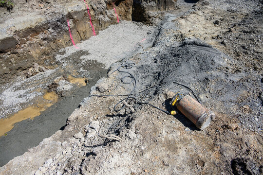 Submersible pump with power cord used to pump water out of trenches dug on construction site, laying on ground ready to use
