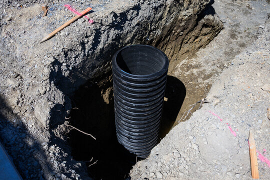 Septic Tank Riser, large black plastic corrugated pipe, installed in trench dug out in dirt of housing development construction project, site preparation detail earthwork
