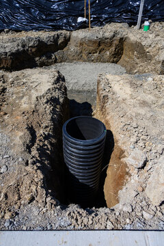 Septic Tank Riser, large black plastic corrugated pipe, installed in trench dug out in dirt of housing development construction project, site preparation detail earthwork
