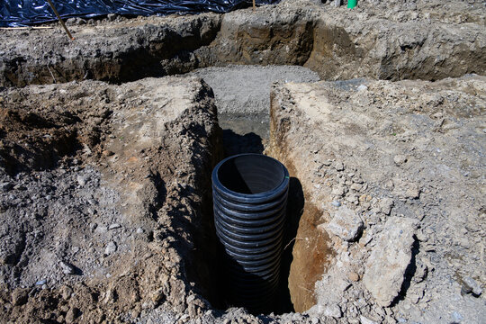 Septic Tank Riser, large black plastic corrugated pipe, installed in trench dug out in dirt of housing development construction project, site preparation detail earthwork
