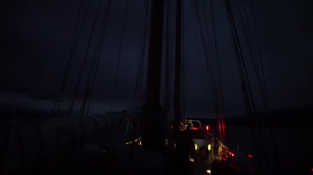 A vertical pan down from the topmast light of the two-masted schooner Amazone, revealing the intricate network of standing and running rigging against a deep night sky during an Antarctic expedition