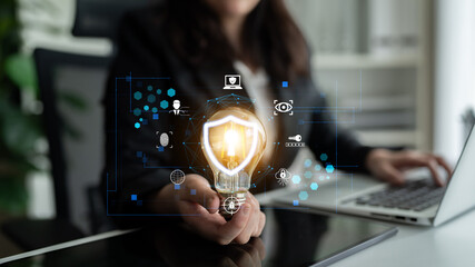 Business professional holding light bulb with digital security icons, symbolizing innovation, technology, and creativity in a corporate environment Fluxor. © InfiniteFlow