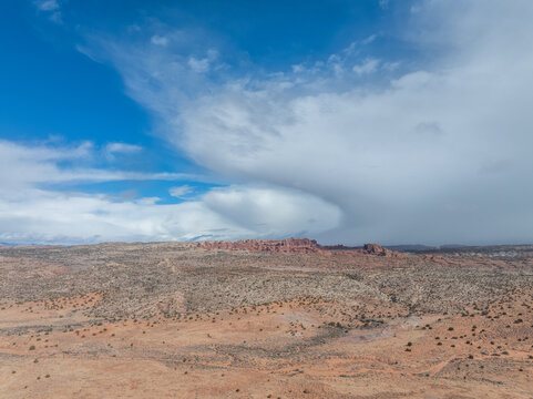 Aerial view of red rock formations and sandstone fins under a dramatic cloudy sky in the desert landscape of Arches National Park Utah, USA.