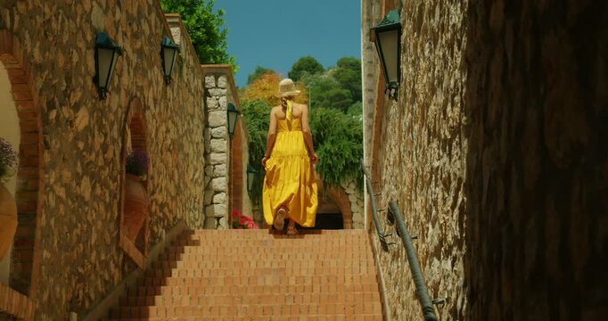 Tourist woman exploring sunny stone alley stairs of coastal town in Capri Italy