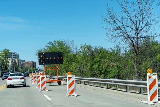 Road work zone with traffic cones and electronic arrow board on city street