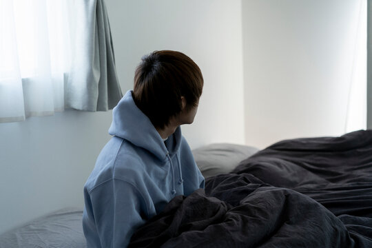 ベッドの上に座っている若い日本人男性