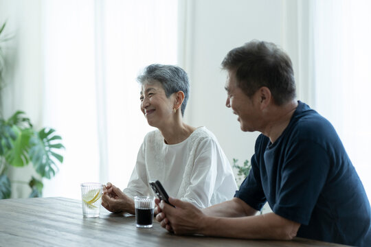 スマートフォンを見ながら談笑する日本人シニア夫婦