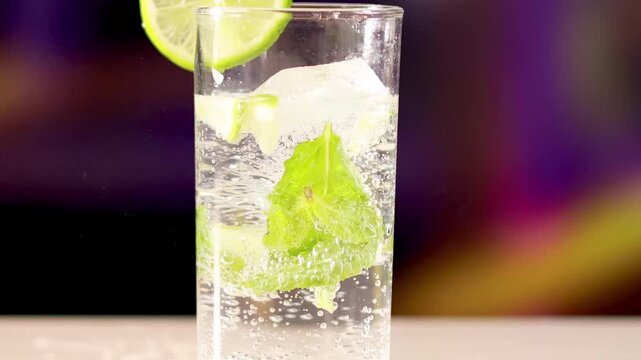 Fresh mojito cocktail with soda water ice cubes mint and lime garnish in tall glass on blurred background.
