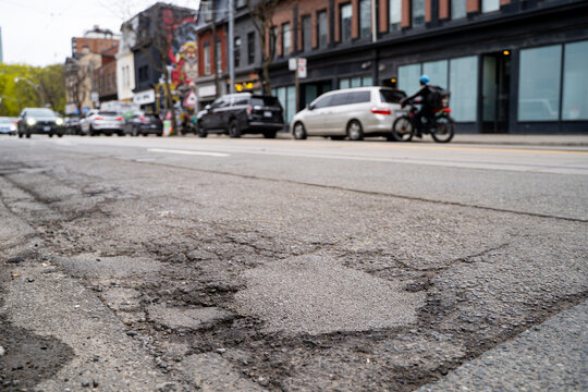 Close up of potholes on damaged asphalt road in urban street.