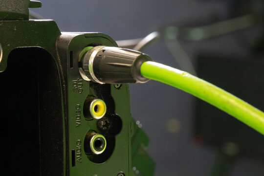 Green Audio Video Cable Plugged Into Device Jack Closeup Showing RCA Ports And Connector
