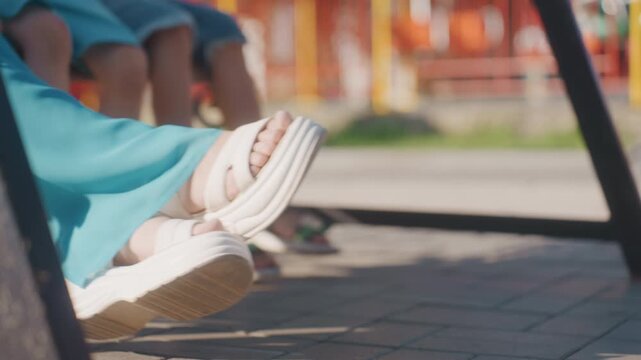 Casual summer outing. Woman enjoying relaxed park moment. Weekend scene with flowing dress and swing enjoyment. Teenage woman on swing with flowing dress and fashionable sandals during sunny day