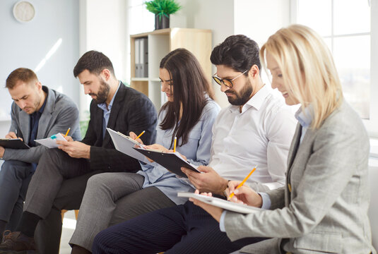 Confident business people in team working together in office meeting, handling paperwork with conversation, focusing on collaboration in a professional setting with dedication and effort.