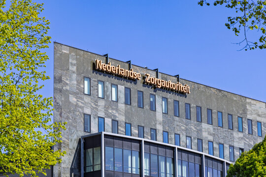 Utrecht, Netherlands, April 28, 2026. Close-up of the Nederlandse Zorgautoriteit (NZa) building facade made of grey stone and glass under a bright blue sky.