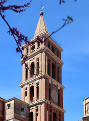 Obraz premium Antico campanile romanico della Chiesa di Santa Maria Maggiore a Tivoli, torre campanaria storica in mattoni rossi adiacente a Villa d'Este, architettura sacra nel centro storico di Tivoli, patrimonio