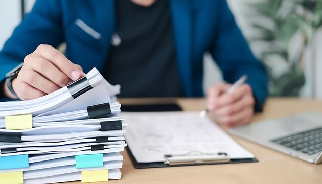 Businessman managing a large stack of documents at an office desk