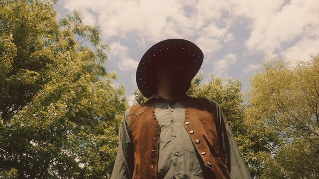Cowboy stands and looks around searching, with trees in background. Shot from a low angle at a high frame rate and edited in classic vintage western film style.
