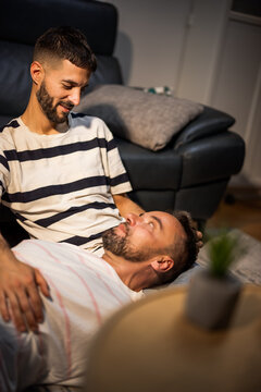 A happy same sex couple sharing an intimate look while relaxing together on a living room sofa.