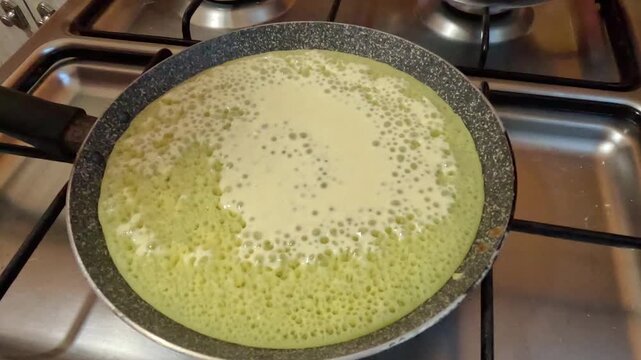 Close-up of Moroccan baghrir cooking in a pan, showing the signature &ldquo;thousand holes&rdquo; surface. Soft spongy pancake forming on one side, highlighting traditional homemade Moroccan cuisine.