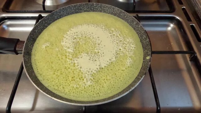 Close-up of Moroccan baghrir cooking in a pan, showing the signature &ldquo;thousand holes&rdquo; surface. Soft spongy pancake forming on one side, highlighting traditional homemade Moroccan cuisine.