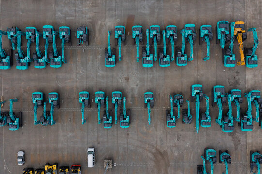 Aerial view of rows of teal excavators and heavy machinery parked at the Port of Antwerp industrial site Antwerpen, Vlaanderen, Belgium.