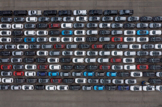 Aerial view of rows of new cars parked at the Port of Antwerp terminal with various colors including white, black, and red Antwerpen, Vlaanderen, Belgium.