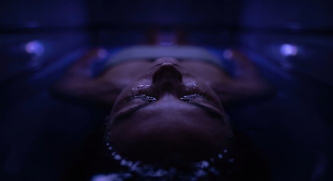 Close up of person floating in dark sensory deprivation tank