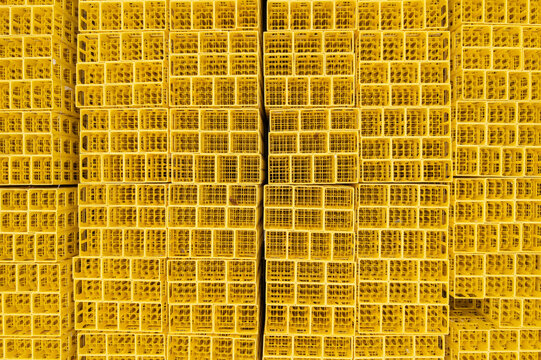 Aerial view of stacked yellow plastic crates arranged in a dense grid pattern in an industrial storage area.
