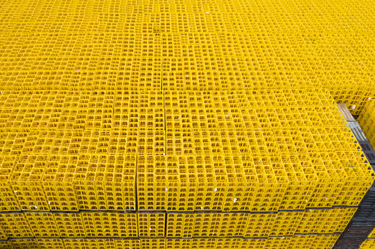 Aerial view of a vast expanse of stacked yellow plastic crates creating a repetitive geometric pattern in an industrial setting.