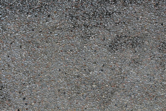 Close-up texture of a grey aggregate concrete surface with small pebbles
