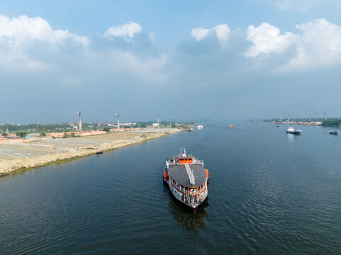 Aerial view of a large passenger launch navigating the Buriganga River near Sadarghat with industrial chimneys on the bank in Dhaka, Dhaka Division, Bangladesh.