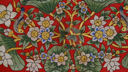 Traditional Thai mural painting of lotus flowers and birds on red background, ornate temple wall art at Wat Pho, Bangkok, Thailand. © PATTASUWANNAKORN