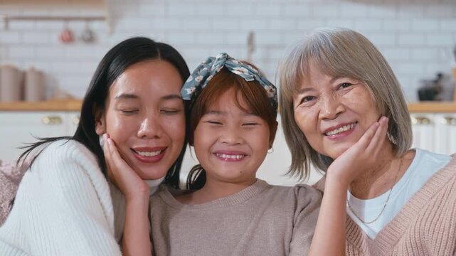 Portrait of three generations of Asian women a cute little girl hugging her mother and grandmother while smiling and enjoying quality family time together at home bonding with love, care, affection