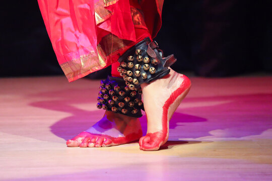 A Bharatanatyam dance artist in traditional saree wearing Ghungroo or metallic bells strung together to form musical anklets.
