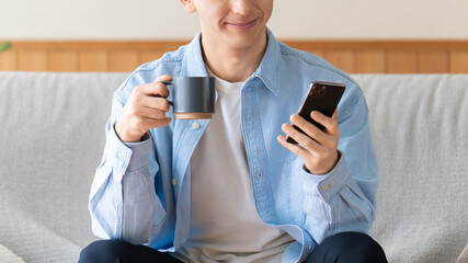 スマートフォンを見ながらコーヒーを飲む男性のライフスタイルイメージ, Man Using Smartphone While Drinking Coffee © Trickster*