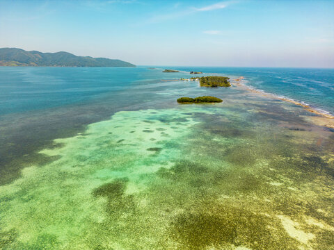 Aerial view of turquoise coral reefs and tropical islands under a clear blue sky Guanaja, Bay Islands Department, Honduras.