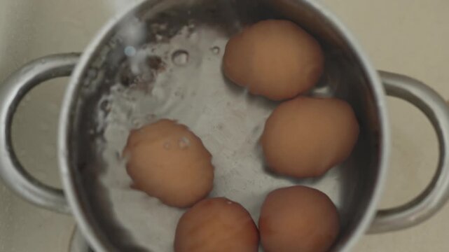 Water pours into a pot with brown eggs creating bubbles