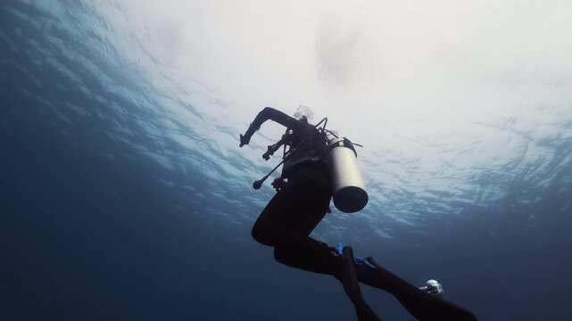 Unrecognizable diver underwater in sunbeams.Technical divers refine their skills undersea. They learn to work with scuba kit and restore emergency, situations that can happen when diving in Ocean