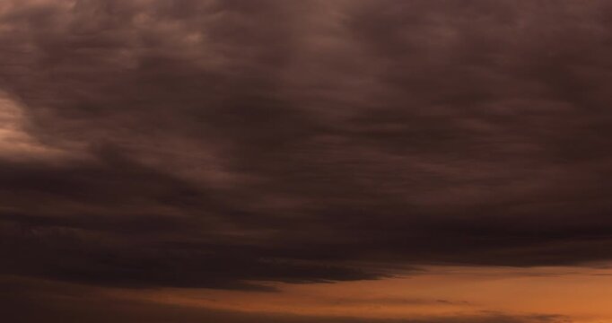 Sunlit clouds move rapidly in a dramatic evening sky filled with warm tones and atmospheric depth.
