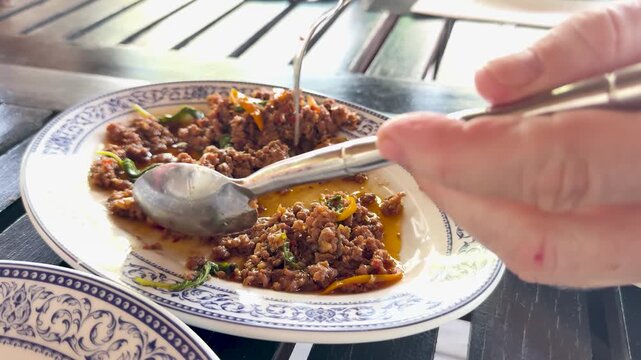 Close up of delicious thai basil stir fried minced pork being served with a fork and spoon.