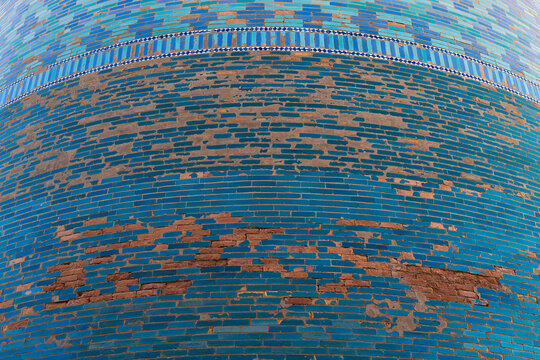 Turquoise glazed tiles and exposed brick on a cylindrical minaret in Ichan Kala old town, Khiva. Ideal for travel publications, heritage content, and architectural texture backgrounds.