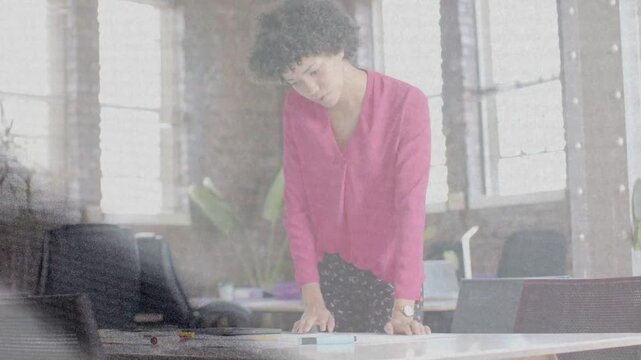 Female designer starting by leaning forward, reviewing layout and nudging tokens on large table