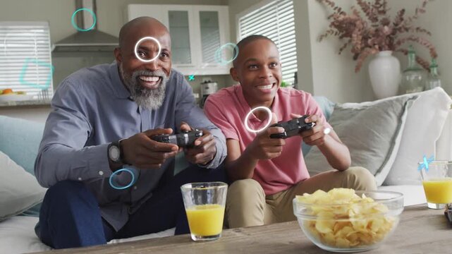 Father and son gaming on couch pressing controllers starting animated overlays, bonding