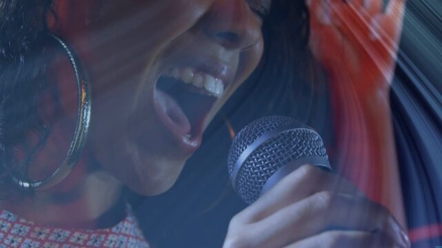 Female singer responding to raised crowd hand, belting into mic in music set under stage lights