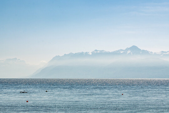 Vue panoramique sur le lac L&eacute;man et les Alpes fran&ccedil;aises depuis Saint-Prex sous un ciel voil&eacute;, Suisse