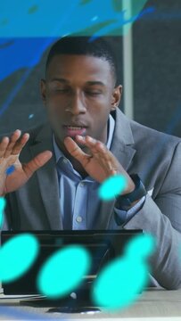 Vertical video: Business exec gesturing at desk, activating teal data overlays and explaining data