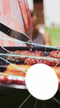 Vertical video: Woman operating grill sliding tongs from left, lifting patties and flipping for bbq