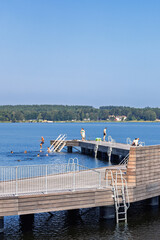 Fototapeta premium Wooden jetty in a lake with bathing people a sunny summer day