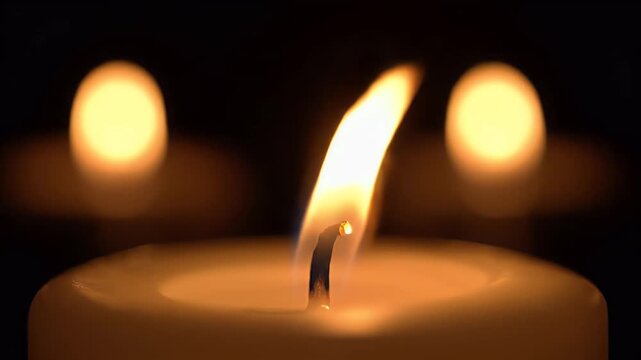 Macro of a white candle flame flickering and swaying in the dark with soft bokeh background