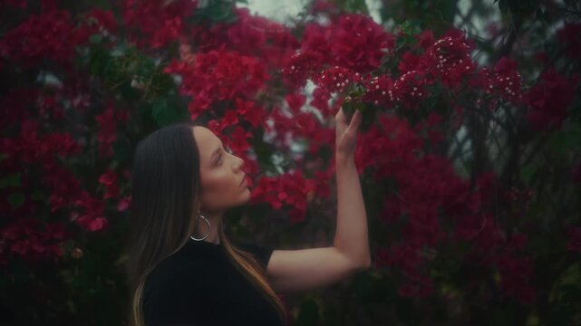 Woman With Flowers. Woman In Garden Delicately Smelling Vibrant Red Flowers With Soft Aesthetic
