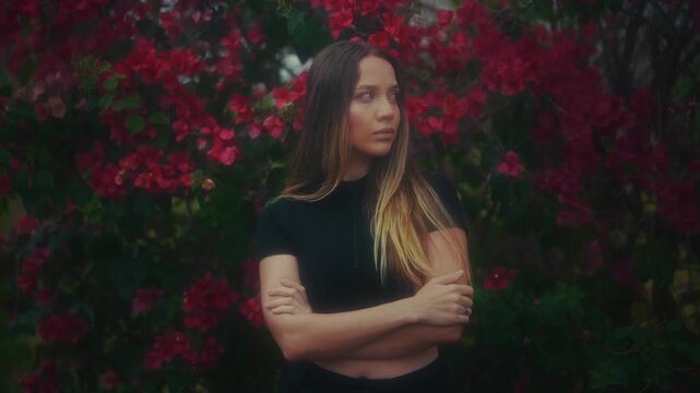 Woman Amidst Vibrant Bougainvillea Thicket. Standing Woman With Crossed Arms And Colorful Backdrop